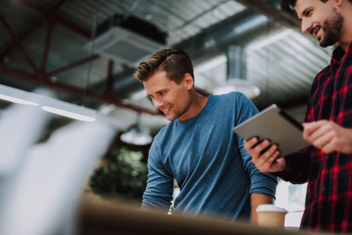 Smiling young man standing in the office with his colleague while being involved in brainstorming