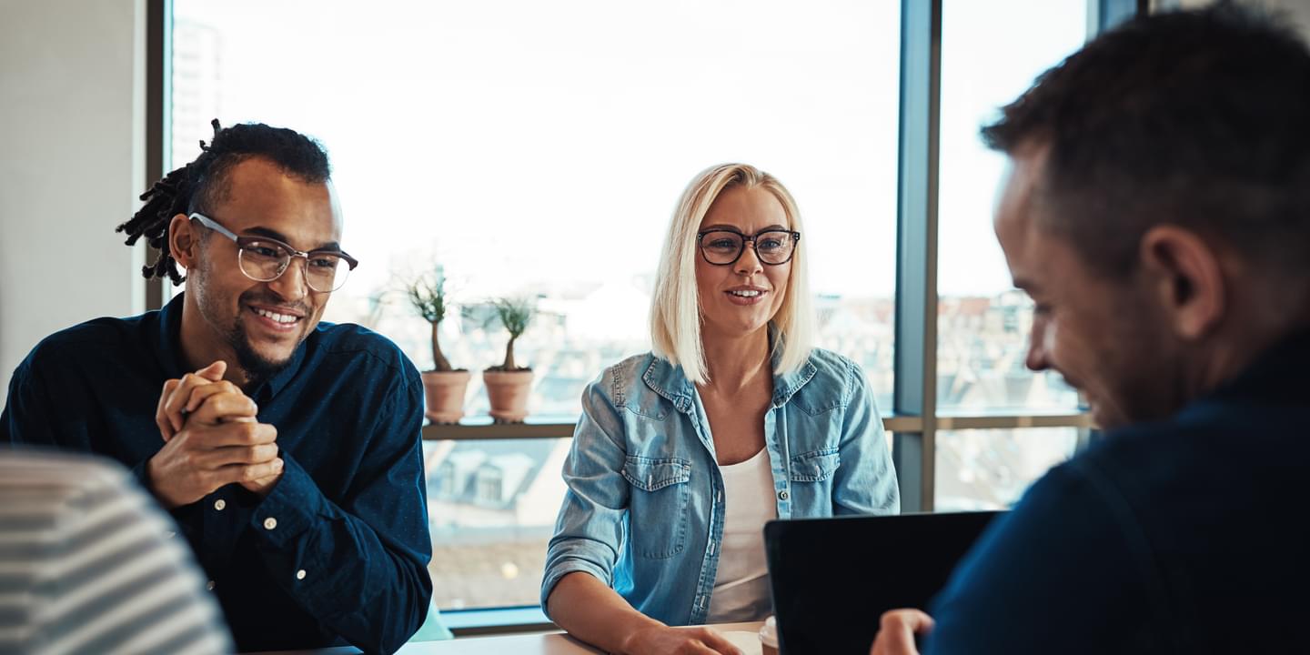 Smiling young colleagues meeting around a table in an office