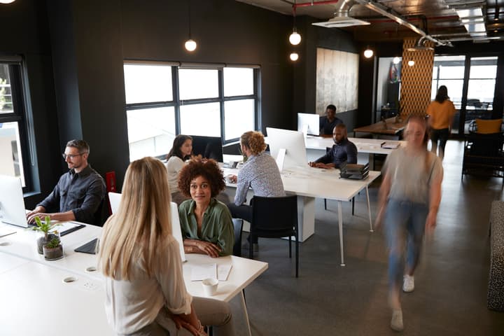 Elevated view of creative business colleagues working at desks and walking through a busy office