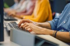 The arms of customer service agents working at a computer at a desk.
