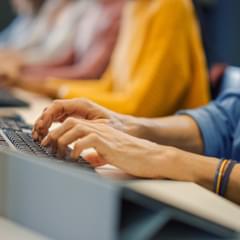 The arms of customer service agents working at a computer at a desk.