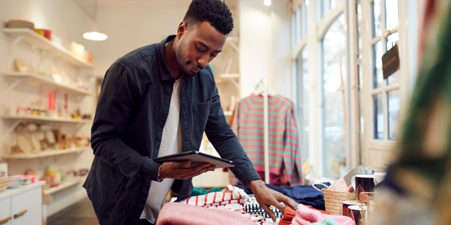 Male Small Business Owner Checks Stock In Shop Using Digital Tablet
