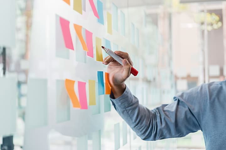 Employees at conference table workers collaborate in discussion and meeting with sticky notes on glass wall