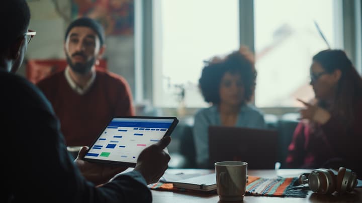 Colleagues sit around a conference table discussing learning management sytems.