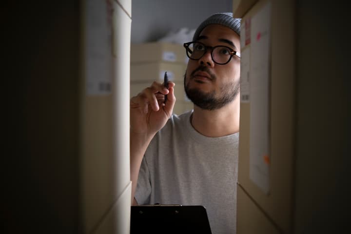 An Asian male checking stock and inventory for an omnichannel business.