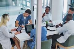 Medical, group and meeting for healthcare in conference room with technology, top view and discussion. Collaboration, doctor and nurse team in boardroom brainstorming