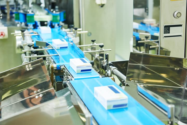 A conveyer belt in a medication production facility is loaded with packages of recently manufactured medication.