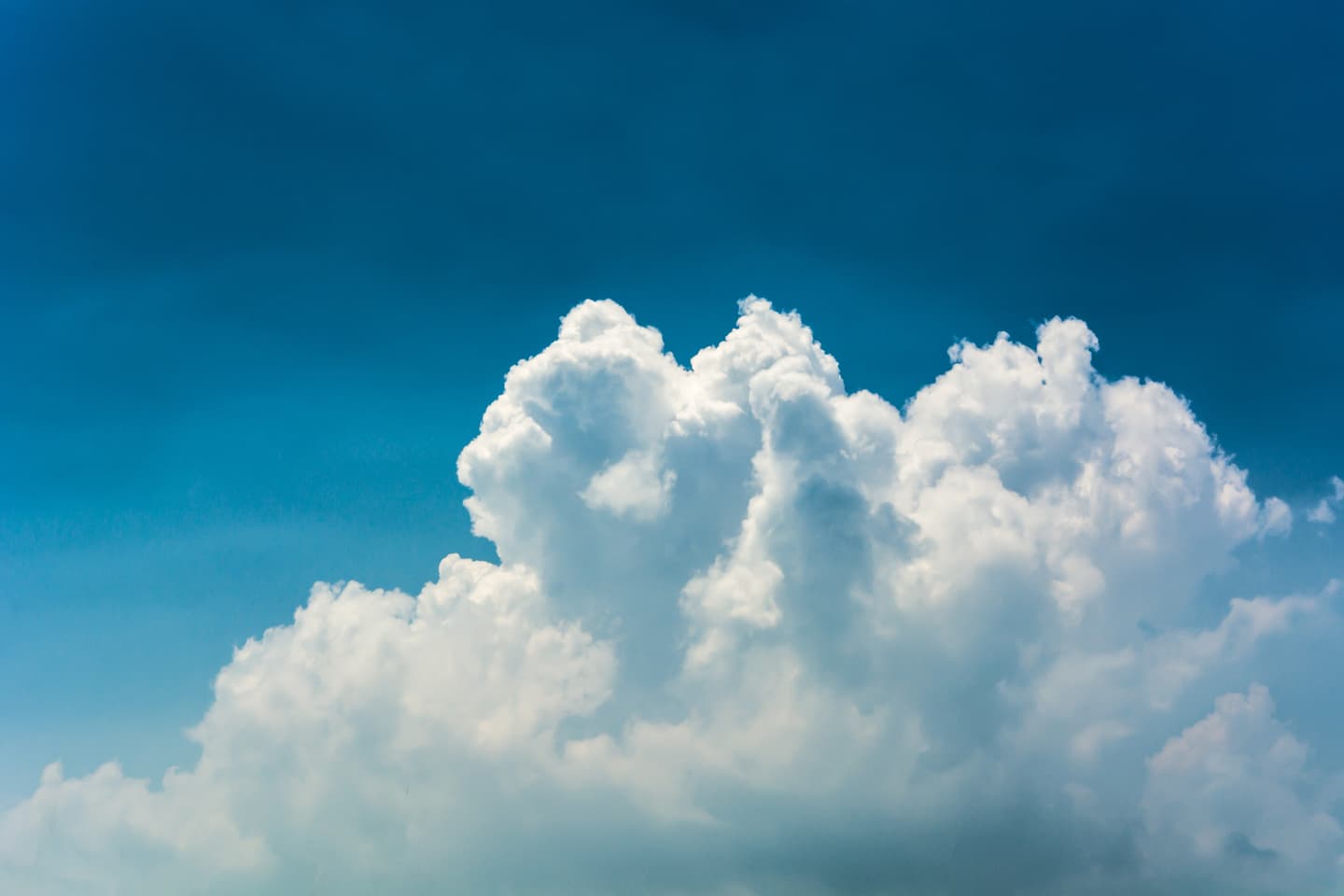 Image of fluffy white clouds on a blue sky. Photo by Alex Machado via Unsplash