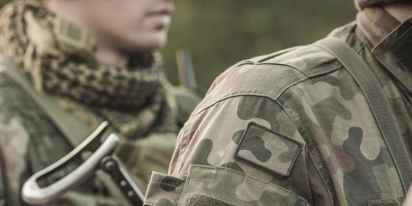 Close up of soldiers wearing camouflage fatigues lined up. The soldiers' faces are obscured.