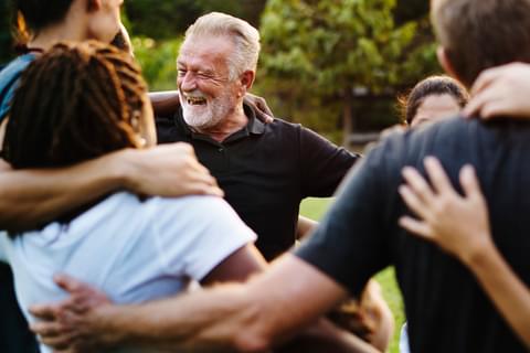 Community group of people smiling and embracing outdoors