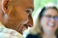 A close up of Propellerite Riley Smith's face in profile. In the background, the image is blurry, but fellow Propellerite Kerri Evans is visible.