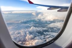 The view outside of an airplane window with a view of the wing of the airplane and sky and clouds
