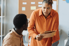 Business people in a workspace communicating and looking at computers and documents.