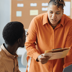 Business people in a workspace communicating and looking at computers and documents.